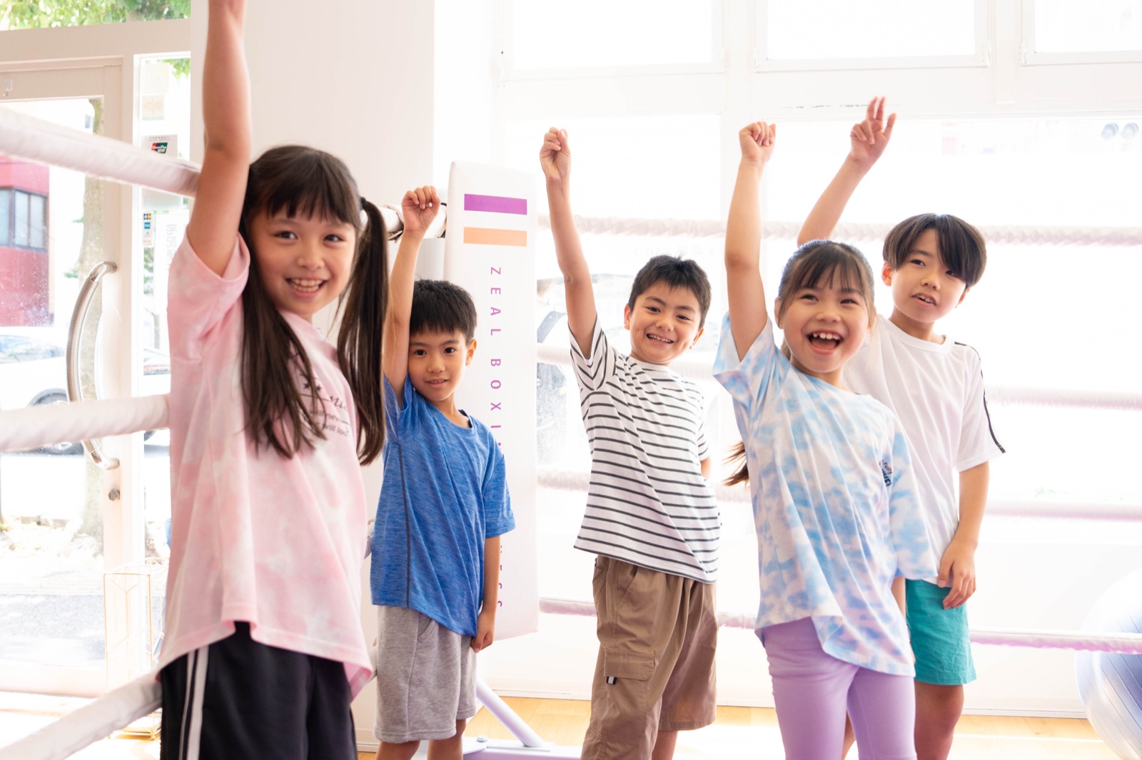 西新エリアからも通える小学生英会話 English Fight Kidsのジムで、コーチと一緒に明るくボールトレーニングを行う子どもたち